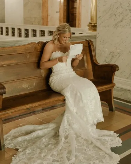 A bride reading a letter on a wooden bench